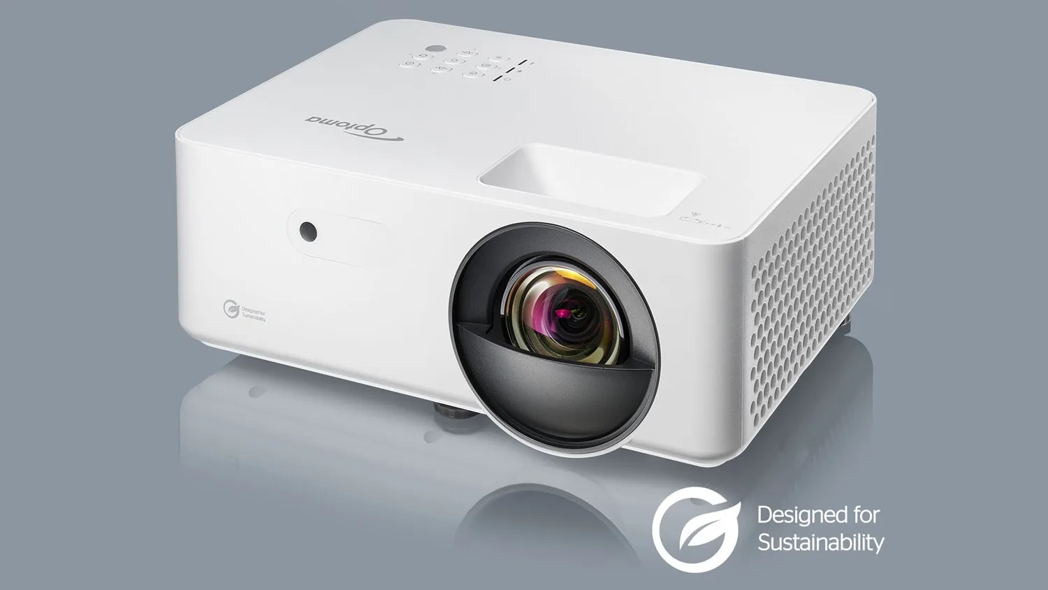 Projecteur blanc compact avec objectif noir et logo de durabilité environnementale, vue de trois quarts sur fond gris.